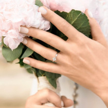 Mano con ramo de novia y anillo de compromiso en oro blanco con 4 circonitas