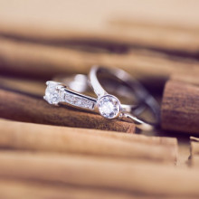 Dos anillos de compromiso en oro blanco y circonitas sobre fondo de madera