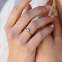 Rosetón de circonitas y oro rosa anillo de compromiso en manos de mujer