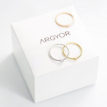 Tres anillos finos de compromiso tipo solitario con circonitas sobre estuche de joyería blanco