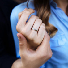 Manos de pareja con anillo de compromiso solitario con diamantes