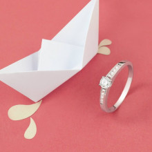 Anillo de pedida con diamantes junto a barco de papel