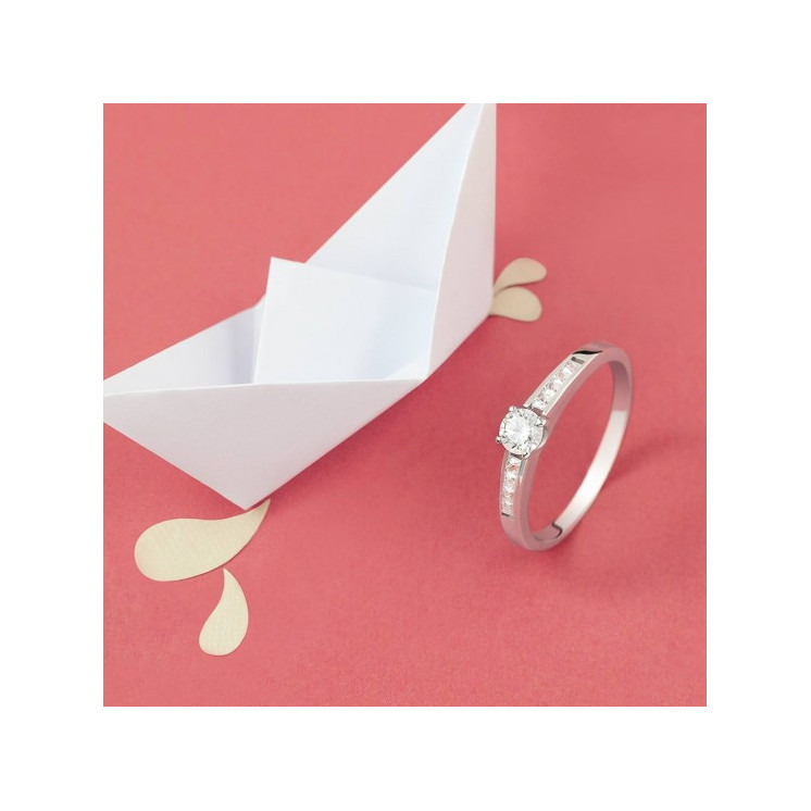 Anillo de pedida con diamantes junto a barco de papel