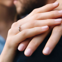 Manos de mujer con anillo de compromiso con diamante engarzado en 2 garras