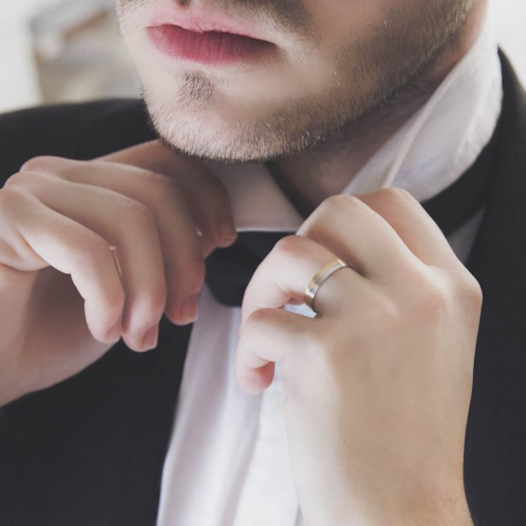 Mano de hombre con alianza de boda en oro bicolor satinado