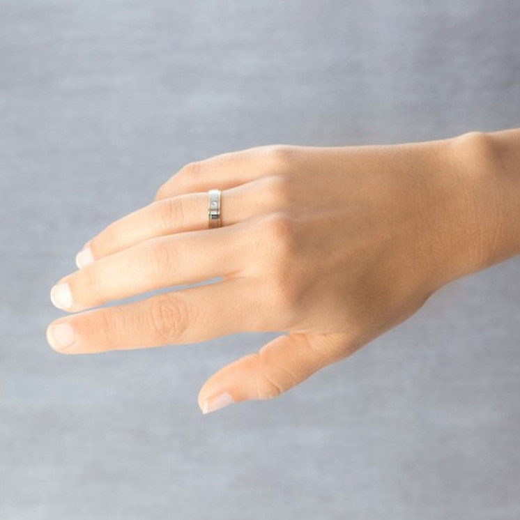 Mano con anillo de boda ancho de 5 milímetros con diamante talla brillante