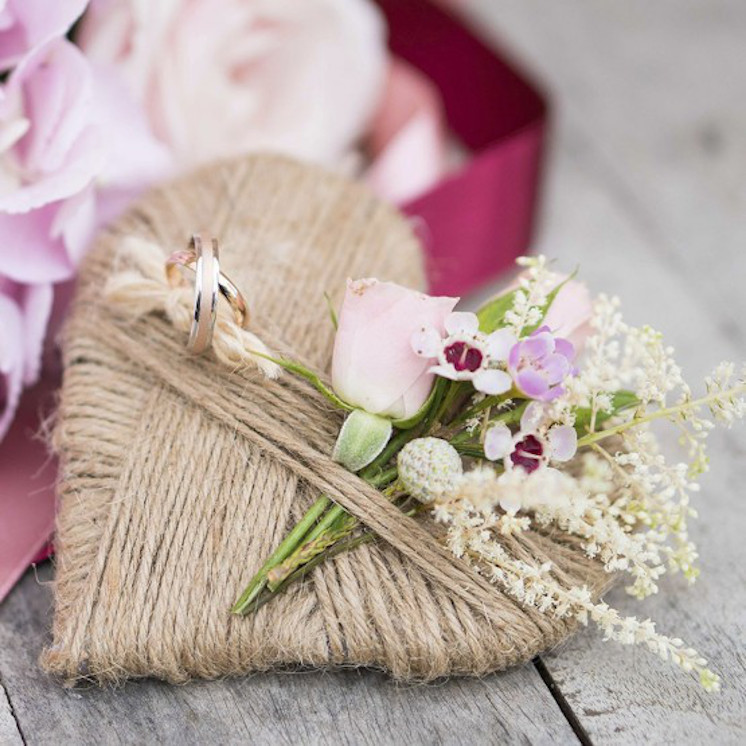 Presentación de alianzas de boda con corazón y flores