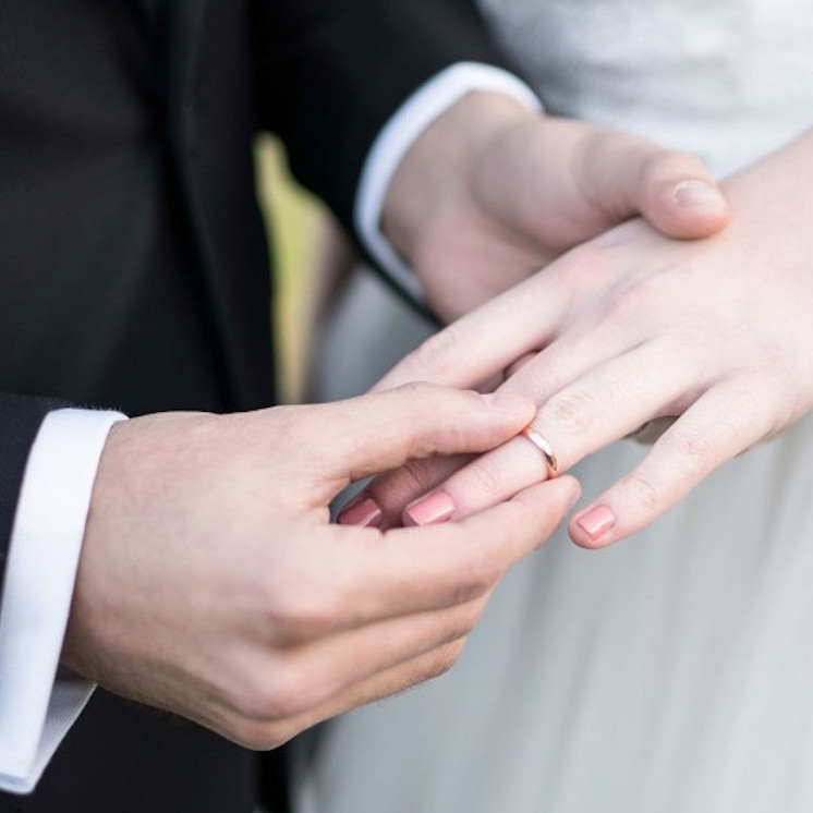 Manos poniendo alianza clásica de boda de oro rosa de 3 milímetros