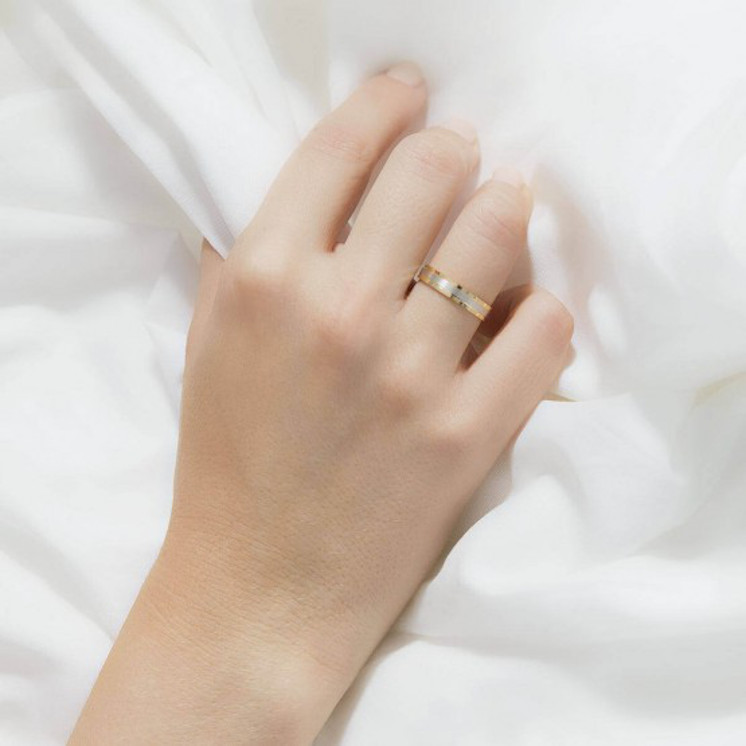 Mano de mujer con anillo de boda plano en oro amarillo con banda central oro blanco satinado