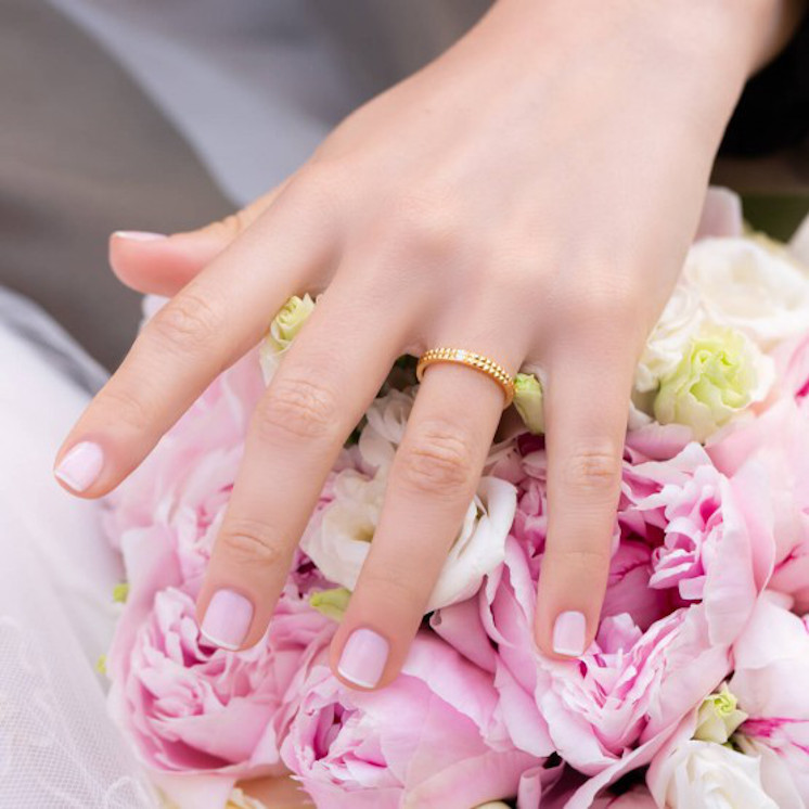 Mano con alianza doble de tachuelas y diamantes