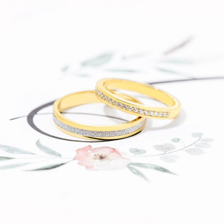 Pareja de anillos de boda bicolor diamantada junto a anillo de compromiso